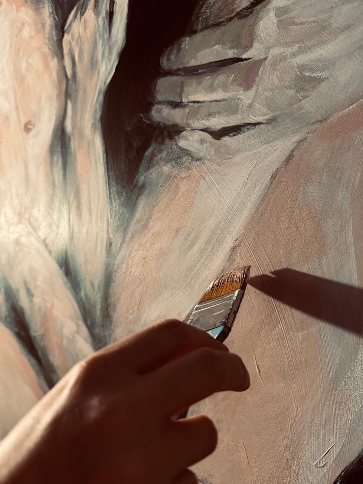 Gros plan sur la main d'Astrid tenant un pinceau au-dessus d'une peinture